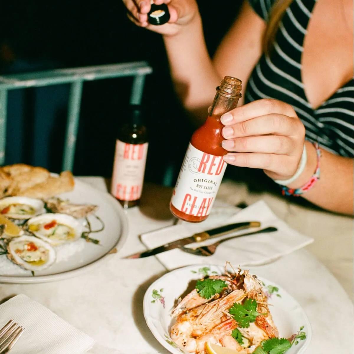 Oysters, shrimp and a bottle of Red Clay hot sauce on a restaurant table