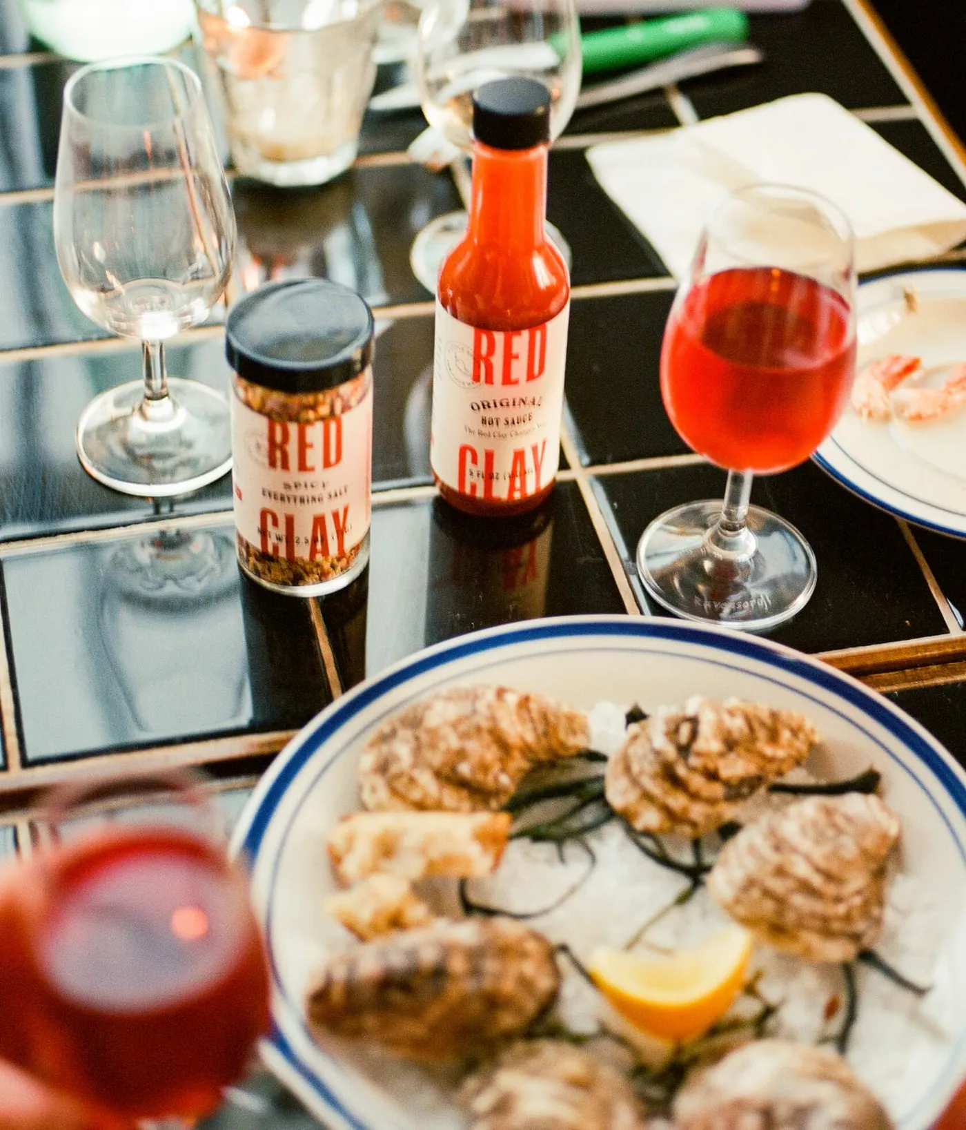 Red Clay bottles on a restaurant table with oysters and drinks