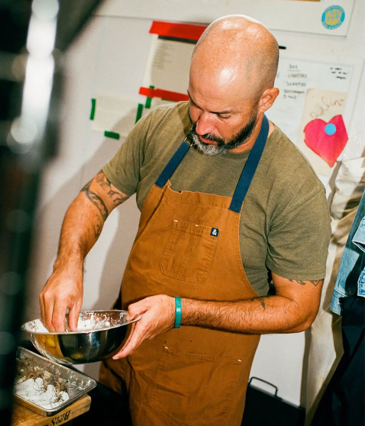 A chef in a canvas apron working at a kitchen counter