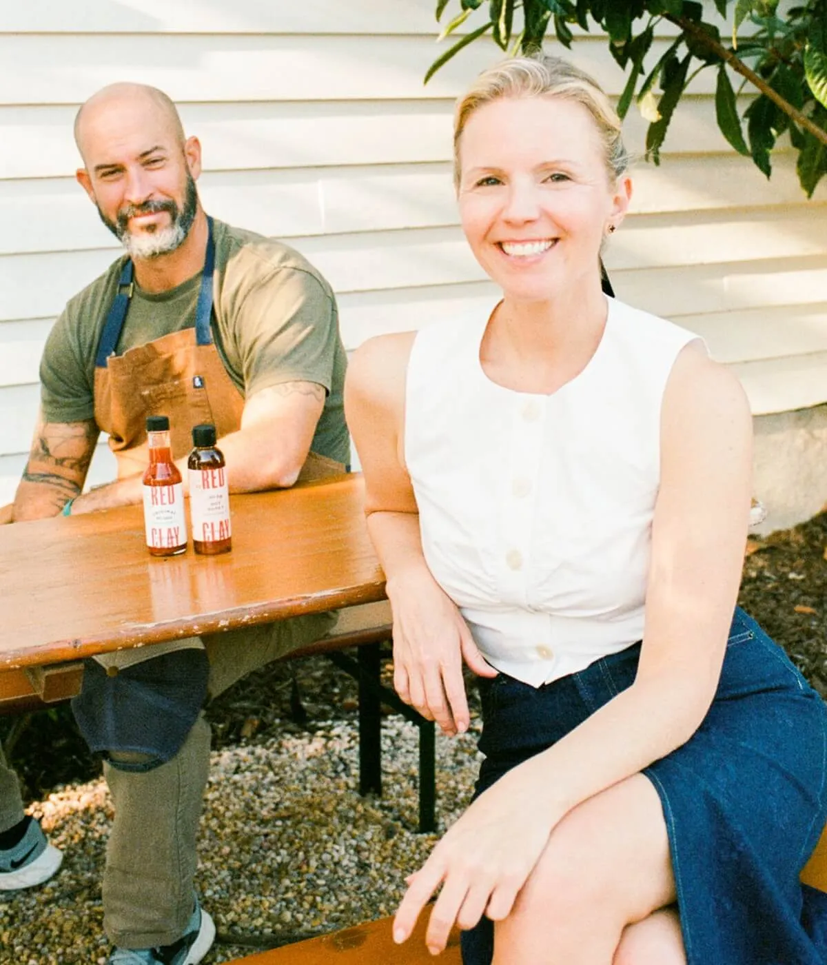 Two people at an outdoor table set with Red Clay bottles